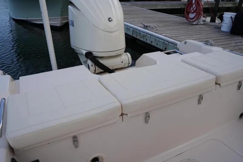 Slide: The Image of 2026 Grady-White 251 Coastal Explorer boat with cushioned seating and outboard motor at dock. - 19