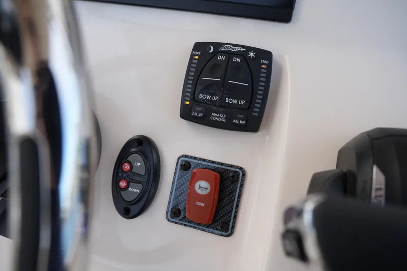 Slide: The Image of 2026 Grady-White 251 Coastal Explorer boat controls, featuring trim tab and horn buttons. - 32