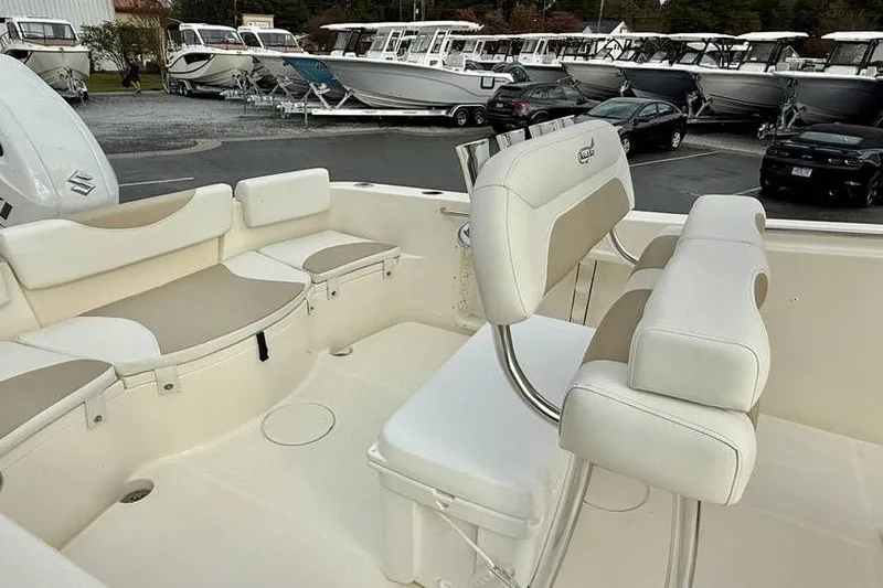 Slide: The Image of 2026 Bulls Bay 230 Center Console boat interior with seating and helm, parked in a marina. - 12