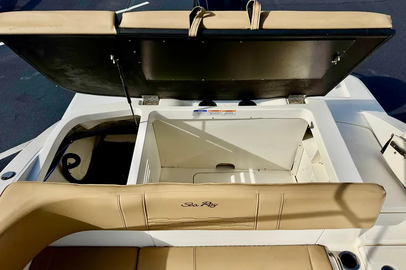 Slide: The Image of 2022 Sea Ray SPX 210 Outboard boat with open storage compartment and beige seating. - 25