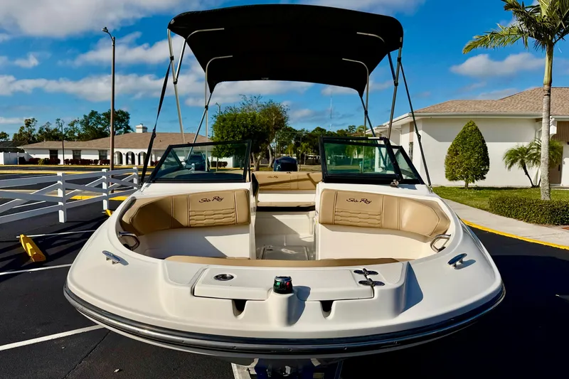 Slide: The Image of 2022 Sea Ray SPX 210 Outboard boat with tan seating and canopy in a sunny setting. - 7