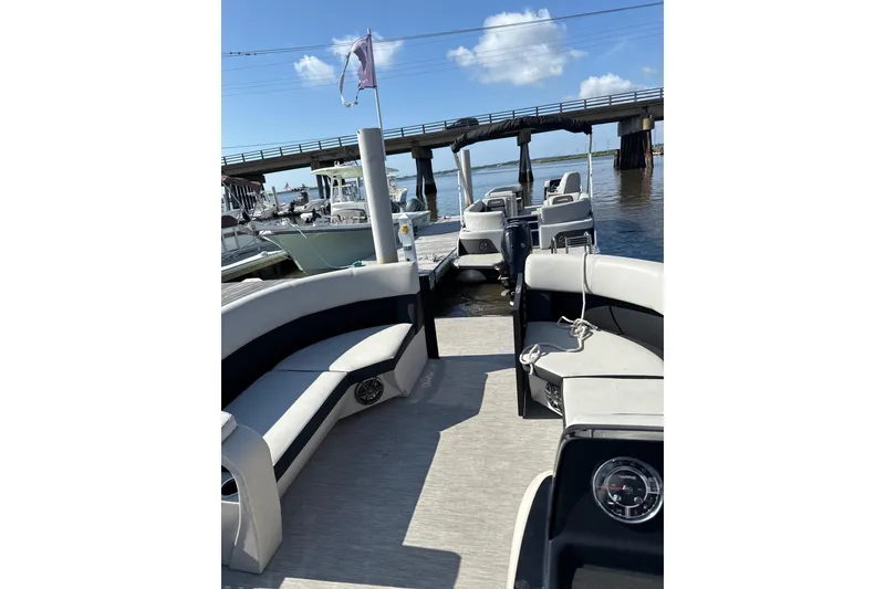 Slide: The Image of 2024 Harris Breeze 230 pontoon boat docked near a bridge on a sunny day. - 5