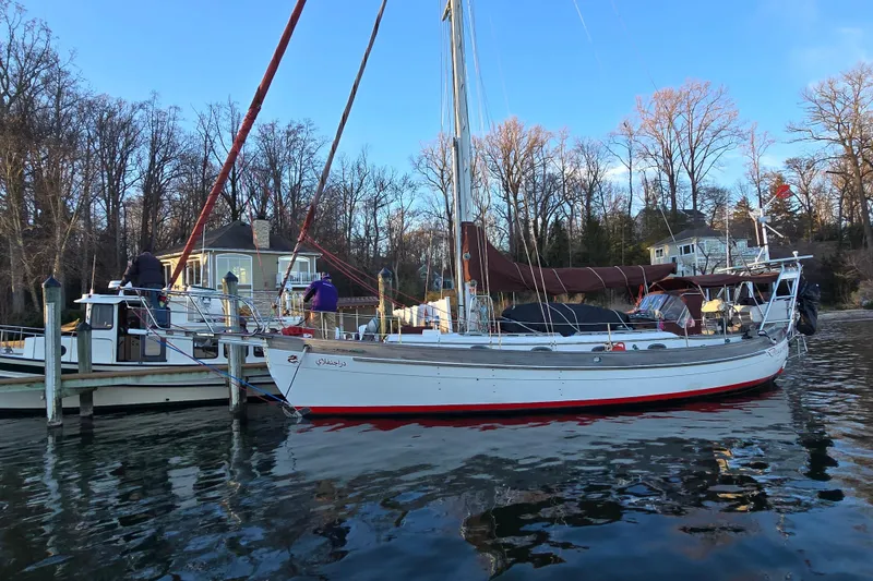 The Image of 1986 Hans Christian 38T sailboat docked by a lakeside home, surrounded by trees. - 0