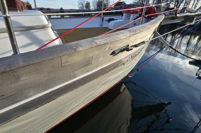 Slide: The Image of 1986 Hans Christian 38T sailboat docked, showcasing wooden hull and deck details. - 7