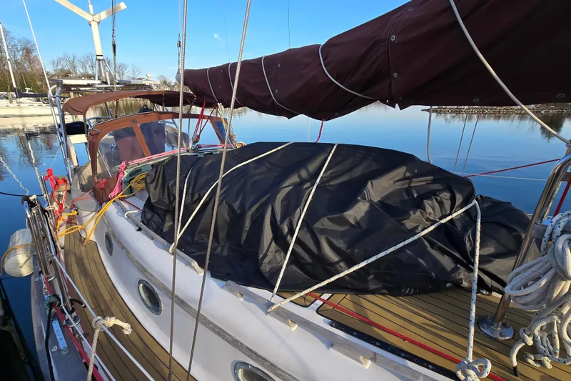 Slide: The Image of 1986 Hans Christian 38T sailboat docked, covered with tarp, clear sky reflection on water. - 9