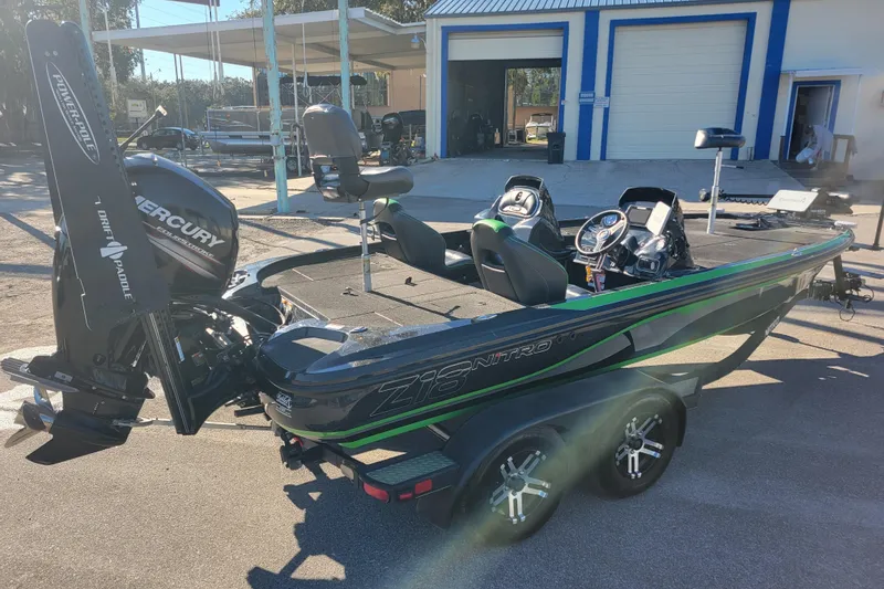 Slide: The Image of 2018 Nitro Z18 boat with Mercury engine, parked outdoors near a blue and white building. - 5