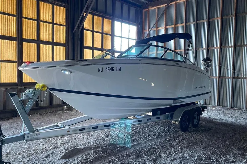 Slide: The Image of 2019 Regal 22 FasDeck boat on trailer in a rustic warehouse setting. - 3
