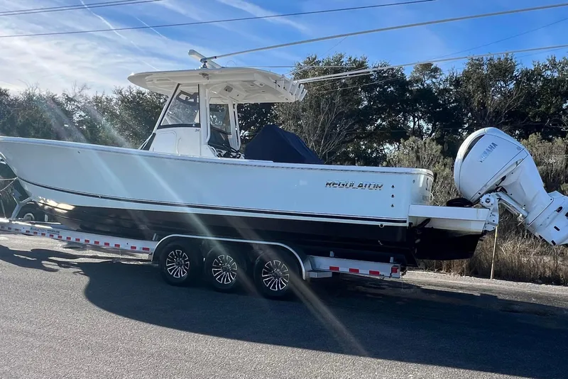 Slide: The Image of 2024 Regulator 34 Center Console boat on trailer, parked outdoors under clear blue sky. - 4