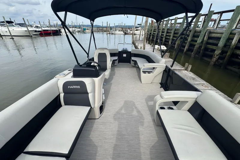Slide: The Image of 2024 Harris Breeze 230 pontoon boat with spacious seating at a marina dock. - 4