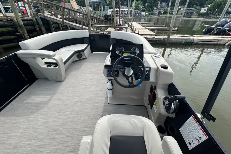Slide: The Image of 2024 Harris Breeze 230 boat interior with steering wheel, seating, and dock view. - 5