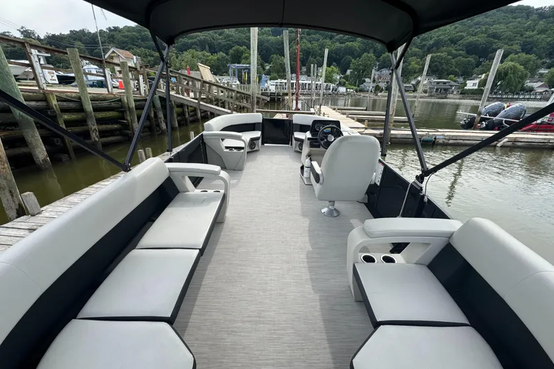 Slide: The Image of 2024 Harris Breeze 230 pontoon boat interior with spacious seating and canopy at a dock. - 6