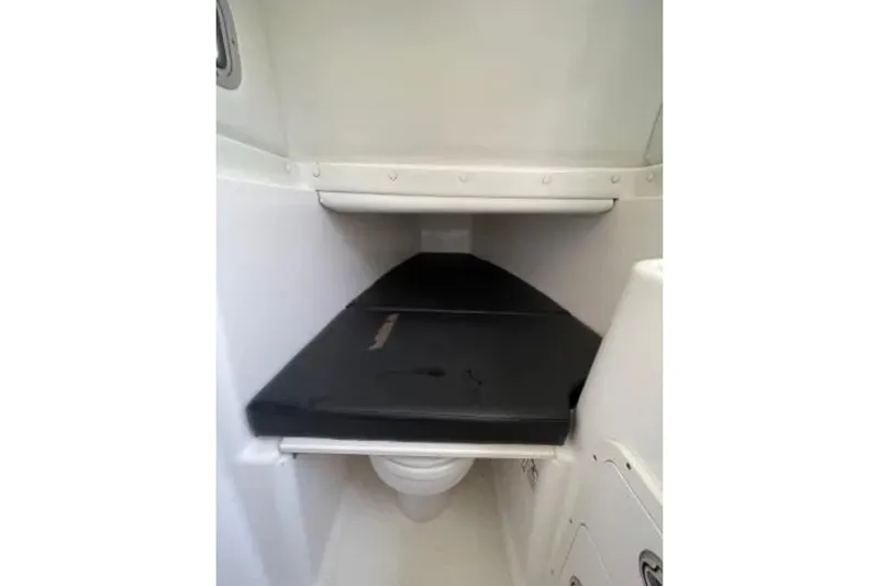 Slide: The Image of 2004 Century 3200 Center Console boat interior with compact toilet and cushioned seat. - 29