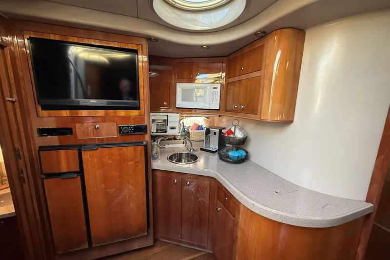 Slide: The Image of 2002 Regal Commodore 3860 yacht kitchen with wood cabinets, TV, and modern appliances. - 15