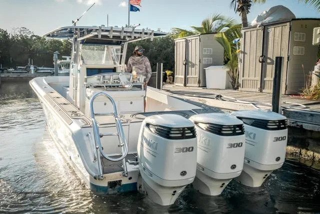 Slide: The Image of 2015 Bahama 34 boat with triple 300 horsepower engines docked near palm trees. - 10