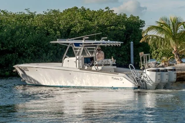 Slide: The Image of 2015 Bahama 34 boat on water, surrounded by lush greenery and palm trees. - 3
