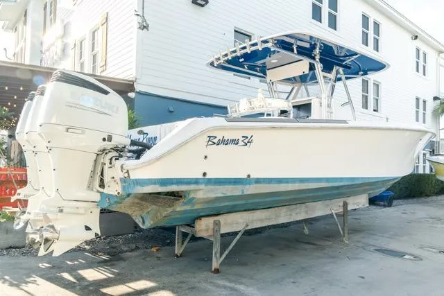 Slide: The Image of 2015 Bahama 34 boat on a trailer, parked near a white building. - 32