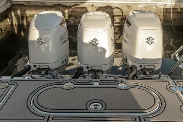 Slide: The Image of Triple Suzuki outboard motors on a 2015 Bahama 34 boat, docked in sunlight. - 41