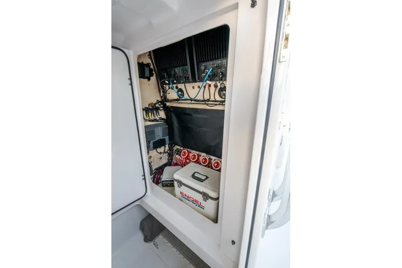 Slide: The Image of Electrical panel inside a 2015 Bahama 34 boat, featuring wiring and an Engel cooler. - 61