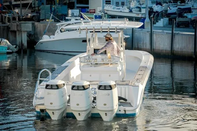 Slide: The Image of 2015 Bahama 34 boat docked, featuring triple outboard engines, with other boats in the background. - 7