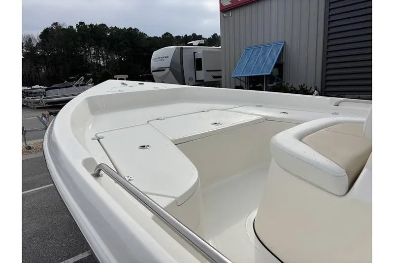 Slide: The Image of 2026 Bulls Bay 2000 boat with white deck and seating, parked near RVs. - 13