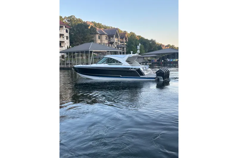Slide: The Image of 2020 Formula 400 Super Sport Crossover boat on calm water near docks. - 3