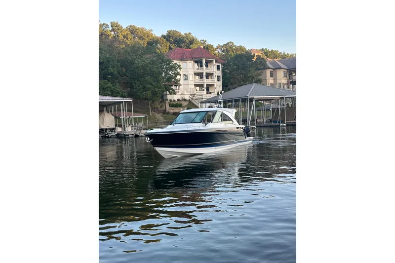 Slide: The Image of 2020 Formula 400 Super Sport Crossover boat on a serene lake near luxury homes. - 5