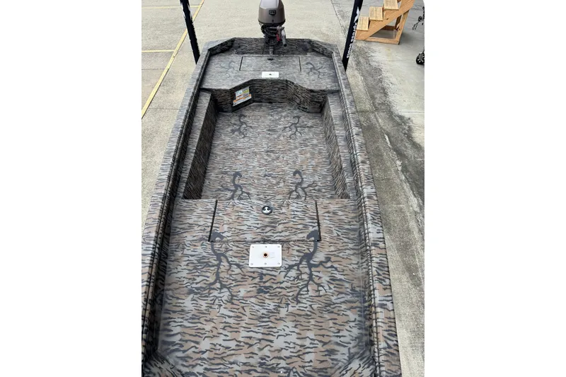 Slide: The Image of 2024 Xpress HD15DBX boat with camouflage interior design, parked on concrete surface. - 2
