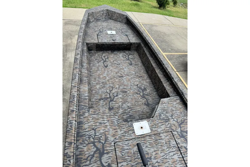 Slide: The Image of 2024 Xpress HD15DBX boat with camouflage interior design, parked on concrete. - 3