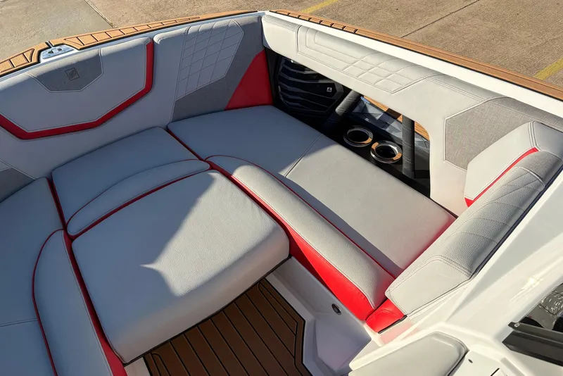 Slide: The Image of 2021 Nautique Super Air Nautique G23 interior with red and gray seating, cup holders. - 14