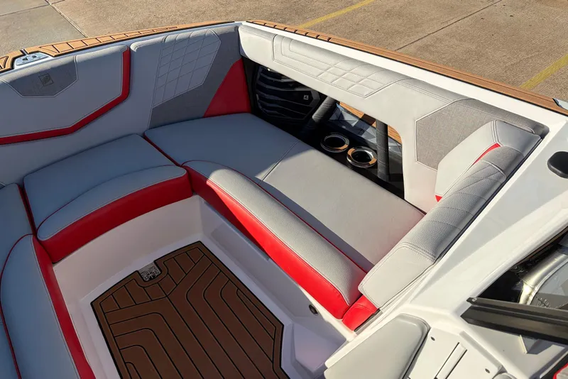 Slide: The Image of 2021 Nautique Super Air Nautique G23 interior with red and gray seating, cup holders, and teak flooring. - 17