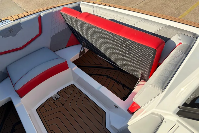 Slide: The Image of 2021 Nautique Super Air Nautique G23 interior with red and gray seating, open storage compartment. - 19