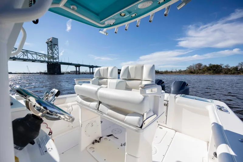 Slide: The Image of 2015 Everglades 255 Center Console boat on water near a bridge, clear sky. - 15