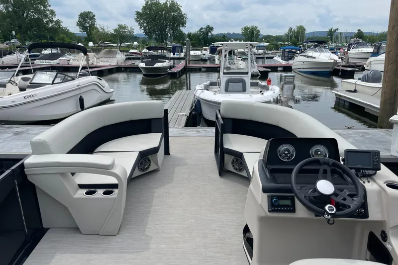 Slide: The Image of 2024 Harris Breeze 230 pontoon boat interior at marina, featuring plush seating and modern dashboard. - 4