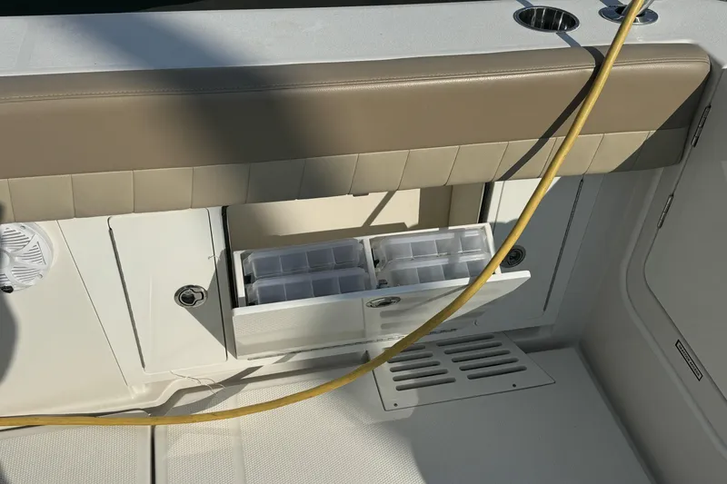 Slide: The Image of 2019 Sailfish 360 CC boat storage compartment with tackle boxes and cushioned seating. - 14