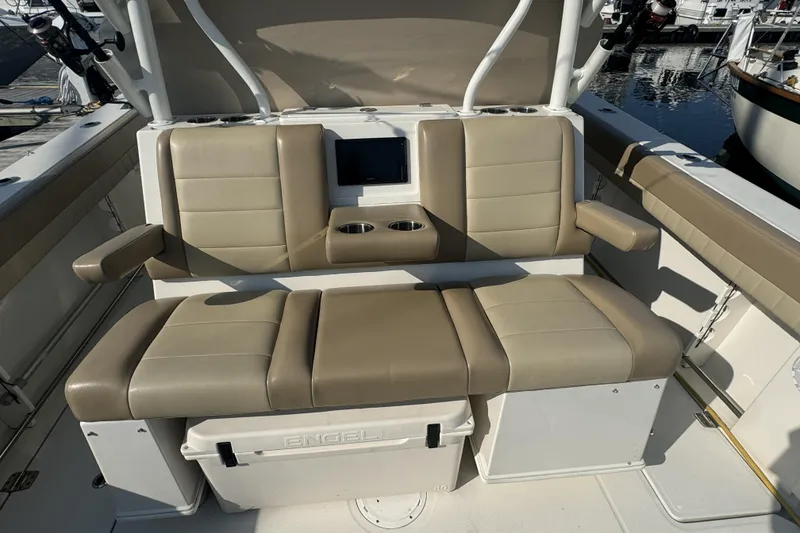 Slide: The Image of 2019 Sailfish 360 CC boat seating area with beige cushions and storage compartment. - 15