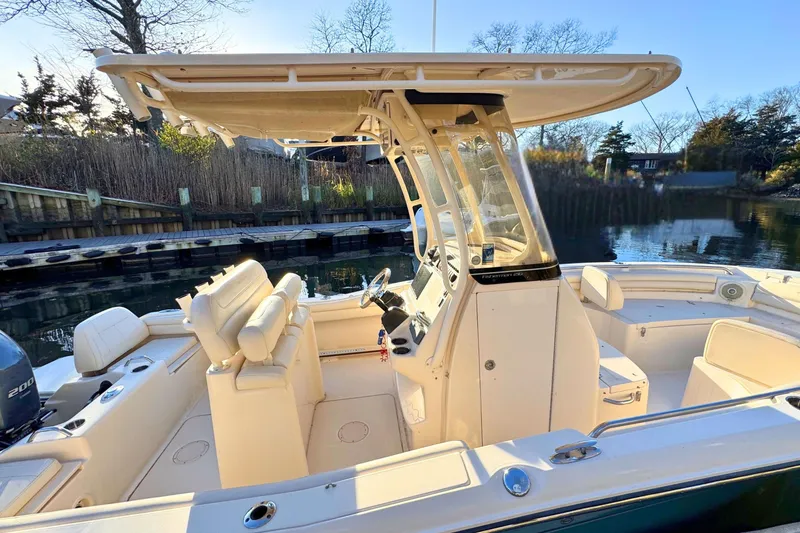 Slide: The Image of 2018 Grady-White Fisherman 216 boat interior with seating and console, docked by a serene waterfront. - 5