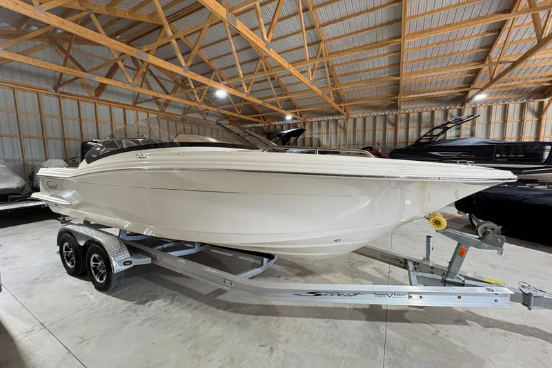 The Image of 2024 Scout 215 Dorado boat on trailer in a wooden storage facility. - 0
