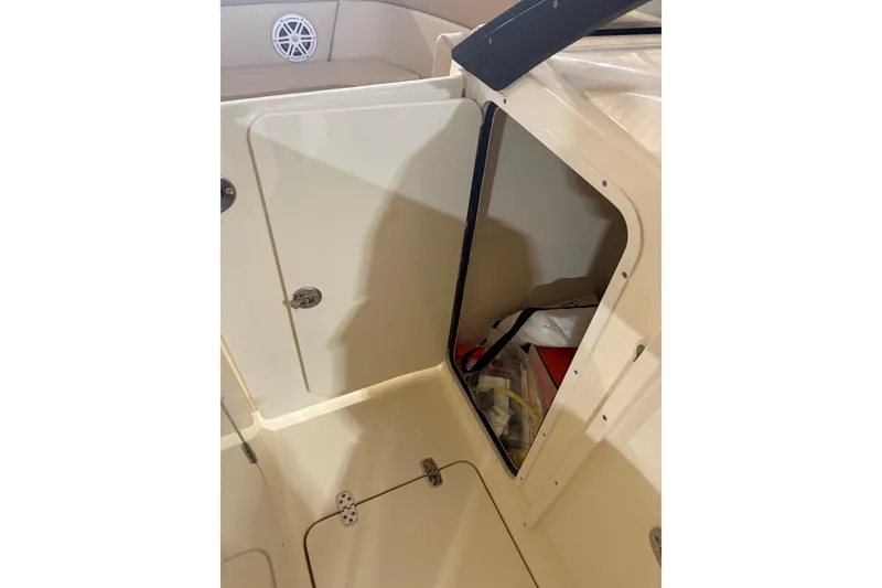 Slide: The Image of 2024 Scout 215 Dorado boat storage compartment with open door, revealing interior items. - 13