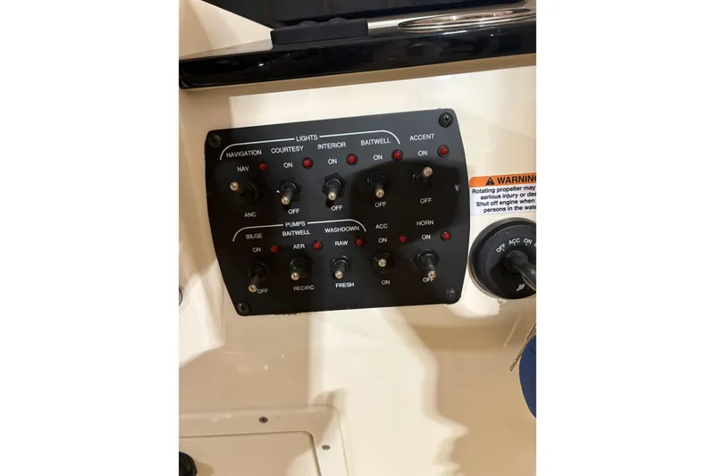 Slide: The Image of Control panel of 2024 Scout 215 Dorado boat with various switches and warning label. - 16