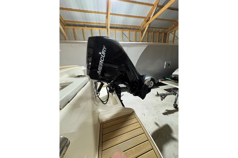 Slide: The Image of 2024 Scout 215 Dorado with Mercury outboard engine in a garage setting. - 19