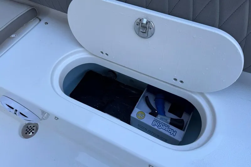 Slide: The Image of Open storage compartment on 2026 Key West 219 FS boat, containing a hose and accessories. - 33