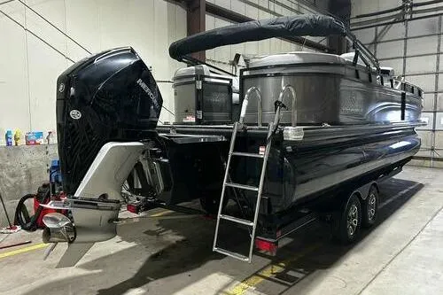 Slide: The Image of 2025 Regency 230 DL3 pontoon boat in warehouse, featuring powerful outboard motor and sleek design. - 2