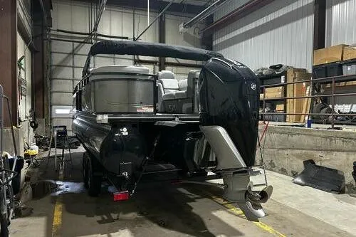 Slide: The Image of 2025 Regency 230 DL3 pontoon boat in a warehouse, rear view with outboard motor. - 3