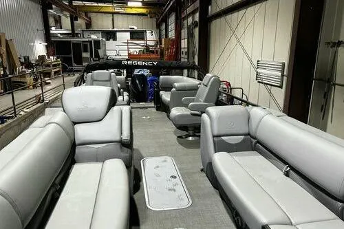 Slide: The Image of 2025 Regency 230 DL3 pontoon boat interior with luxurious seating in a spacious warehouse. - 4