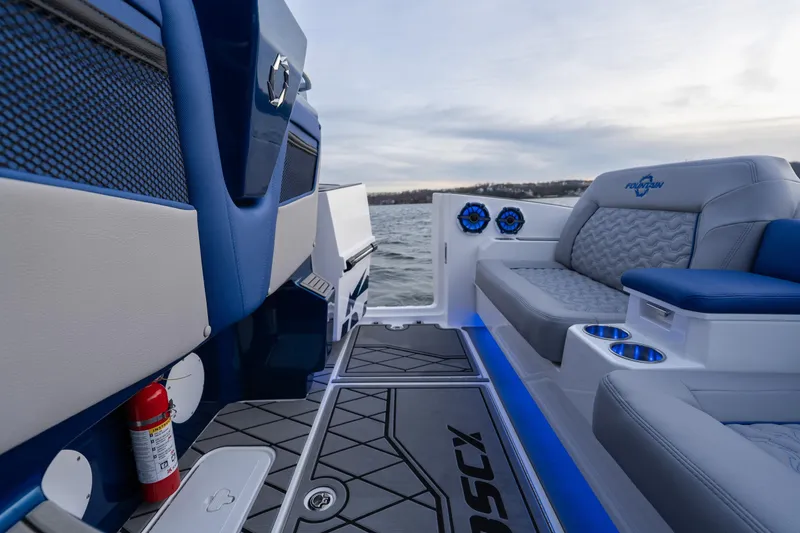 Slide: The Image of 2026 Fountain 38 SCX boat interior with blue and gray seating, cup holders, and ocean view. - 22