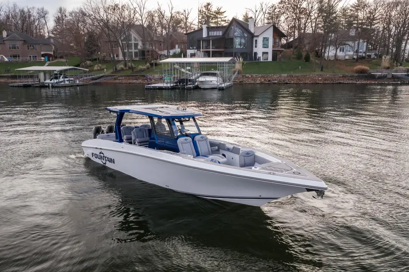 Slide: The Image of 2026 Fountain 38 SCX boat cruising on a serene lake near waterfront homes. - 5