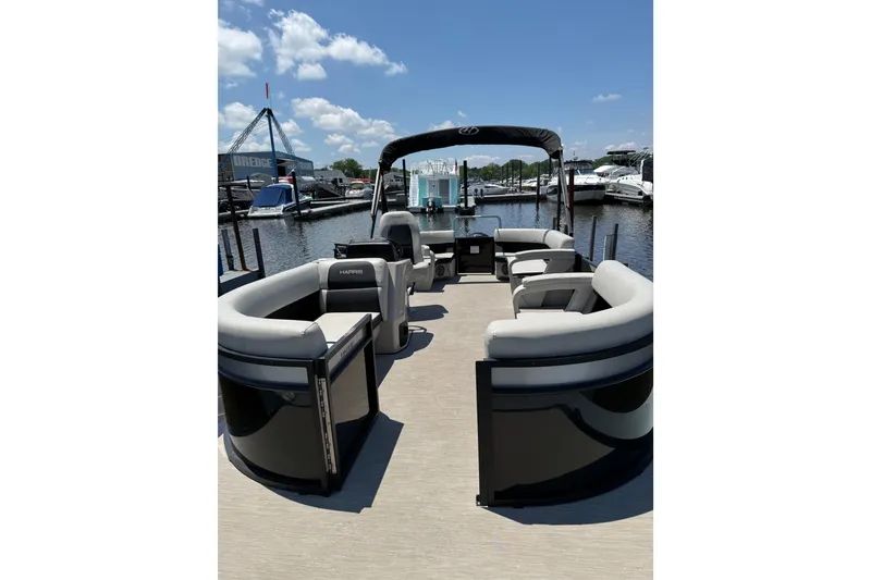 Slide: The Image of 2024 Harris Breeze 230 pontoon boat with spacious seating at a marina. - 2