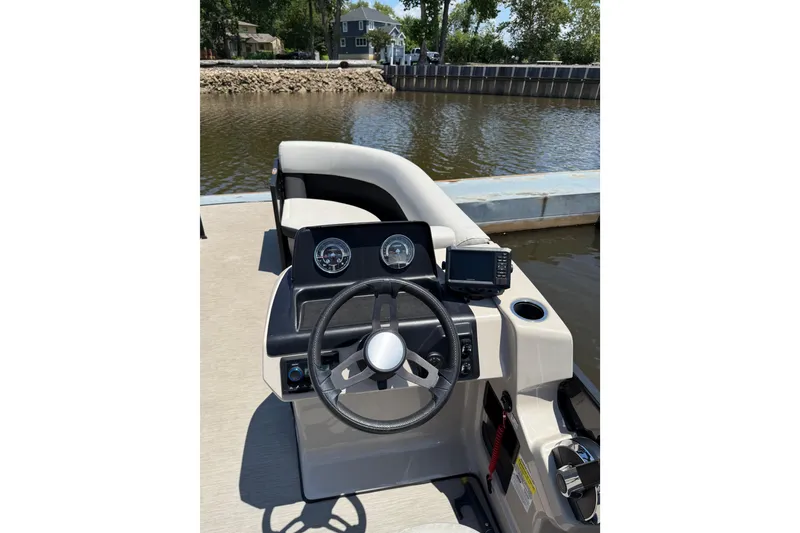 Slide: The Image of 2024 Harris Breeze 230 boat dashboard with steering wheel and gauges by the water. - 5