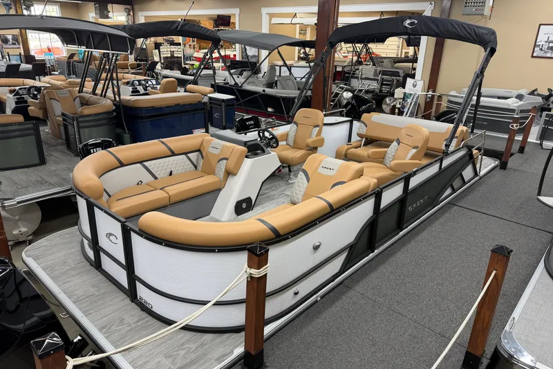 The Image of 2025 Crest Classic 220 pontoon boat with tan seating in showroom display. - 1