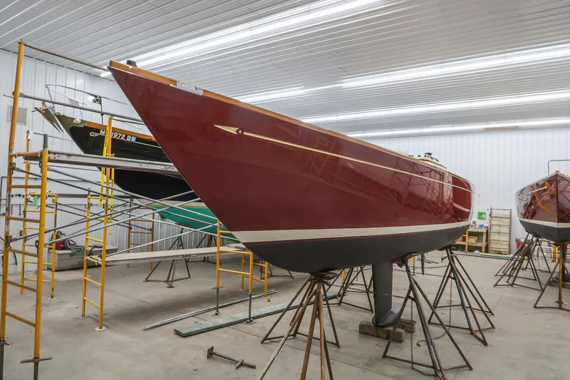 Slide: The Image of Red Morris M29 sailboat from 2011 in a workshop, supported by scaffolding. - 24